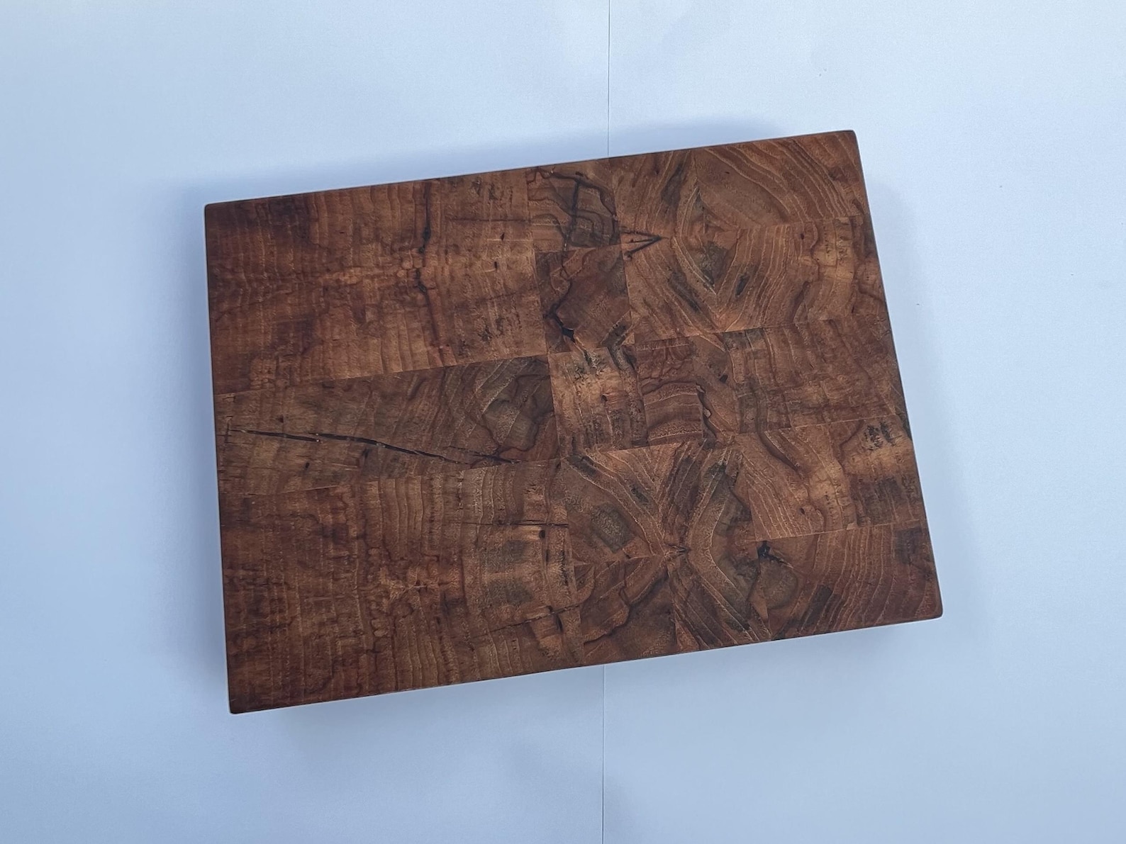 Small pecan end-grain cutting board viewed from above, showing dark brown grain and natural figure